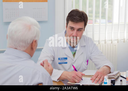 Belarus, Gomel, 31. Mai 2017. Central Hospital. Arzt und Patient. Ein älterer Mann in der Arztpraxis. Der Mann an der Rezeption in der medizinischen Aus Stockfoto