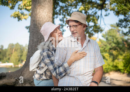 Liebevolle Frau mit Hut ihr schöner Mann umarmen Stockfoto