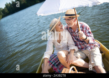 Mann mit Regenschirm beim Sitzen im Boot mit Frau Stockfoto