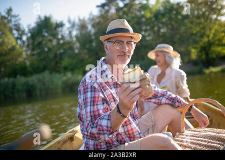 Man gesund essen Sandwich, während mit Bootsfahrt mit Frau Stockfoto