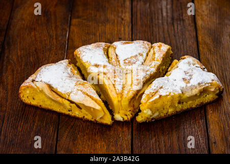 Frisch gebackenen Apfelkuchen mit Zucker Pulver auf einem Holzbrett. Hausgemachte Apfelkuchen. Stockfoto