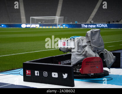 04. Oktober 2019, Berlin: Fußball: Bundesliga, Hertha BSC - Fortuna Düsseldorf, 7. Spieltag im Olympiastadion. Eine Fernsehkamera abgedeckt mit einer Plane steht vor dem Spiel in das leere Stadion am Spielfeldrand. Foto: Soeren Stache/dpa-Zentralbild/dpa - WICHTIGER HINWEIS: In Übereinstimmung mit den Anforderungen der DFL Deutsche Fußball Liga oder der DFB Deutscher Fußball-Bund ist es untersagt, zu verwenden oder verwendet Fotos im Stadion und/oder das Spiel in Form von Bildern und/oder Videos - wie Foto Sequenzen getroffen haben. Stockfoto
