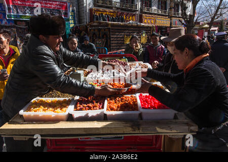 Kunden kaufen Frucht von einem Verkäufer in einem offenen Markt auf der Straße in der Innenstadt von Lhasa, Tibet. Stockfoto