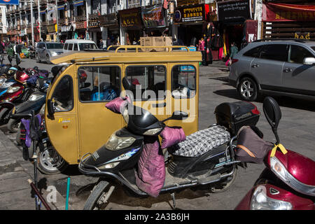 Roller und winzige Auto-rikschas entlang der Straße im asiatischen Hauptstadt Lhasa, Tibet geparkt sind wirtschaftlich motorisierte Verkehrsmittel. Stockfoto