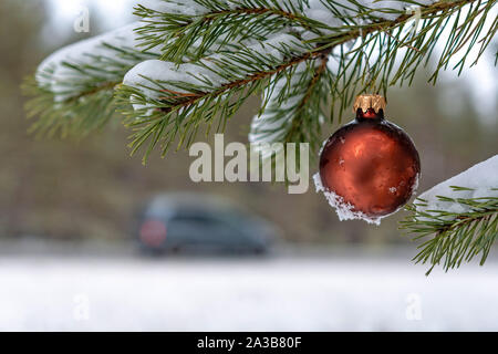 Red christmas Ball auf den verschneiten Tannen Filiale neben der Autobahn. Stockfoto