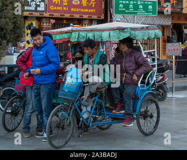 Eine fahrradrikscha ist eine allgemeine Form von wirtschaftlicher Transport in Asien. Ein Passagier wird aus der Kabine am Barkhour Square in Lhasa, Tibet. Stockfoto