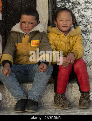 Zwei junge tibetische Kinder, ein Junge und ein Mädchen, für ein Portrait auf den Stufen des Potala Palast in Lhasa, Tibet posieren. Ein UNESCO Weltkulturerbe. Stockfoto