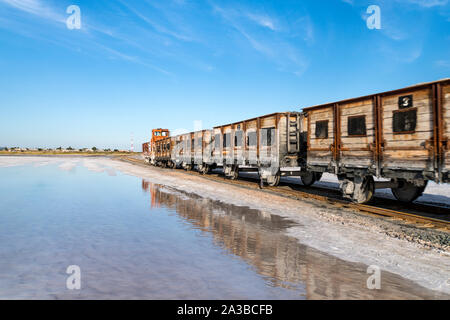 Alte Bahn Fahrten mit der Bahn in das Wasser durch die salt lake gelegt. Zug fährt aus dem Wasser. Abgebaute Salz im See Burlin. Altai. Russland. Bursolith. Stockfoto