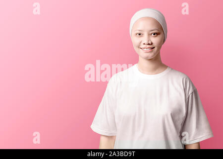 Asiatische Frau in einem weißen Hemd mit einem Lächeln auf ihrem Gesicht stehen über rosa Hintergrund. Krebs Bewusstsein Stockfoto