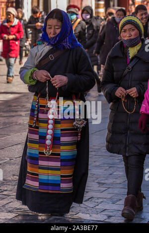 Eine ältere Khamba tibetischen Frau pilgrim in traditioneller Kleidung circumambulates den Jokhang Tempel mit ihrer Tochter in modernem Kleid in Lhasa, Tibet. Stockfoto