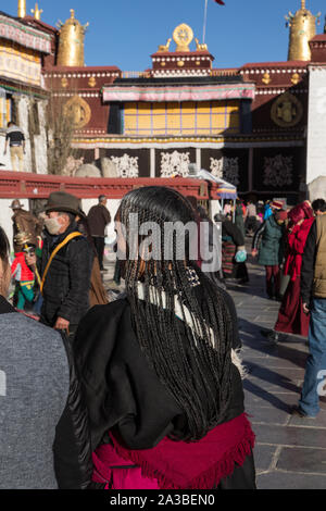 Eine ältere tibetische Frau pilgrim circumambulates den Jokhang Tempel mit ihrem Haar in kleinen Zöpfen. Lhasa, Tibet. Trägt den traditionellen chupa Gewand. Stockfoto