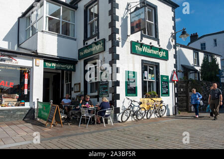 Menschen Touristen sitzen außerhalb der Wainwright Bar Inn Lake Road Keswick Lake District National Park Cumbria England Großbritannien Großbritannien Stockfoto