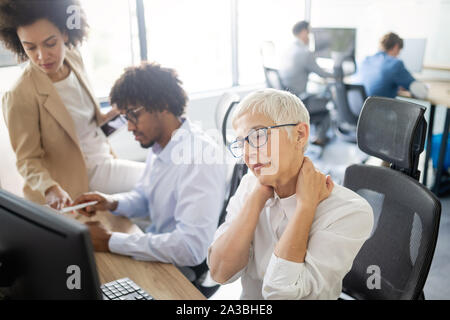 Ausgereifte Frau, Stress und Kopfschmerzen im Büro Stockfoto