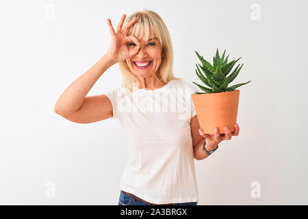 Mittleres Alter Frau mit Cactus pot stehend über isoliert weißer Hintergrund mit glücklichen Gesicht lächelnd tun ok Zeichen mit der Hand am Auge durch fin Stockfoto