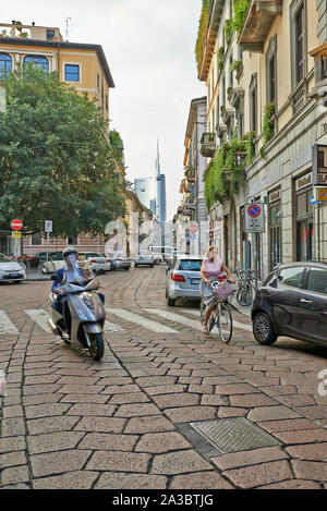 Mailand, Italien - 11. Juni 2015: Mann auf Roller und Frauen mit dem Fahrrad auf der Straße in Milano, Italien. Stockfoto