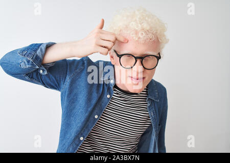 Junge albino blonder Mann tragen Jeanshemd und Gläser über isoliert weißer Hintergrund zeigen unglücklich auf der Stirn zu Pickel, hässliche Infektion von blackh Stockfoto