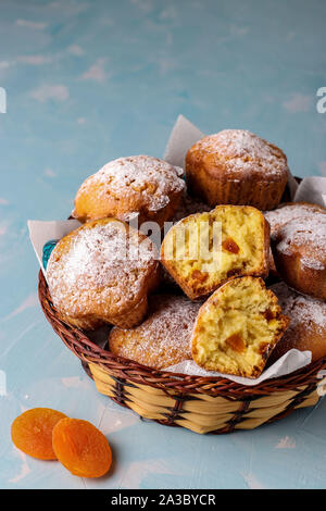 Hausgemachte Muffins mit getrockneten Aprikosen bestreut mit Puderzucker auf einem hellblauen Hintergrund, vertikale Ausrichtung, Kopie Raum Stockfoto