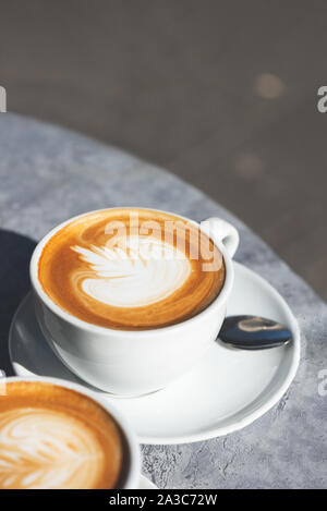 Zwei Tassen flache weiße Kaffee im Café, in der schönen, sonnigen Tag, Schatten auf dem Tisch Stockfoto