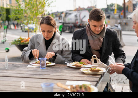 Junges Paar Essen in ein Restaurant im Freien in der Stadt mit der Familie oder mit Freunden genießen Sie ein Mittagessen Stockfoto