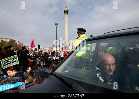 Der Treiber der Leichenwagen, der sich mit einem Fahrradschloss mit Lenkrad verbunden hat, als sein Fahrzeug verwendet wird, die Straße an der Kreuzung von Whitehall und Trafalgar Square während das Aussterben Rebellion protest London zu blockieren. Stockfoto