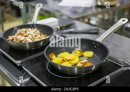 Champignon Pilze und Kartoffeln braten und Brutzeln in Pfannen Stockfoto