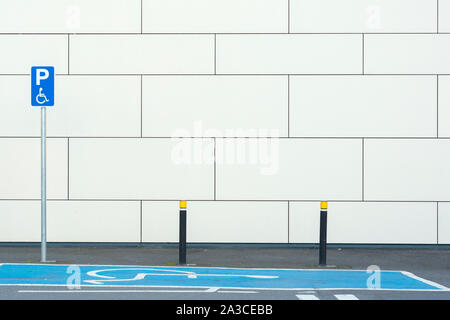 Leerer Behindertenparkplatz mit blauer Markierung und Schild für behinderte Rollstuhlfahrer an der Wand auf einem Parkplatz oder Parkplatz in Killarney, Irland Stockfoto