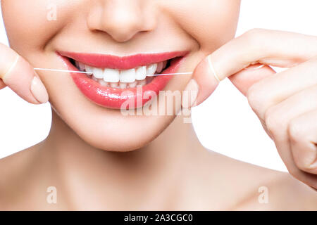 Junge schöne Frau ist bei der Reinigung der Zähne beschäftigt. Schönes Lächeln Gesunde weisse Zähne. Ein Mädchen hält einen Zahnseide. Das Konzept der Mundhygiene. Stockfoto