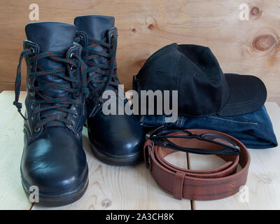 Schuhe, Gürtel, Hüte, Sonnenbrillen und Jeans, platziert auf einem Holzboden. Stockfoto