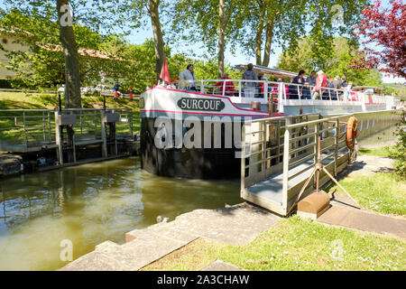 Die Surcouf touristische Kreuzfahrt flachen Boot im Emborrel Schleusen am Canal du Midi, der offenen Tore öffnet es Reisen auf dem Kanal, um fortzufahren Stockfoto