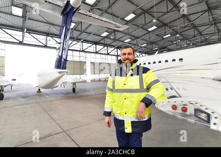 Portrait einer flugzeugmechaniker in einem Hangar mit Jets am Flughafen - Kontrolle der Flugzeuge für Sicherheit und Technische Funktion Stockfoto