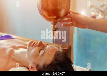 Ayurveda Massage alternative heilende Therapie. Schöne kaukasisch Weiblich, shirodhara Behandlung liegen auf einem Holztisch in Indien Salon Stockfoto