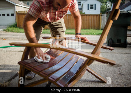 Ein Handwerker poliert einem handgefertigten Holzstuhl außerhalb Stockfoto