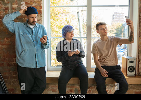 Gruppe von Happy kaukasischen jungen Leute, hinter dem Fenster. Gemeinsame Nutzung einer News, Fotos oder Videos von Smartphones, wodurch selfie oder Spiele spielen und Spaß haben. Soziale Medien, moderne Technologien. Stockfoto