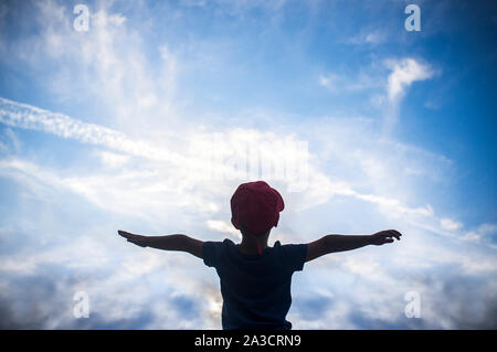 4 Jahre alter Junge vorgibt, über bewölkter Himmel zu fliegen. Kinder Phantasie Konzept fördern Stockfoto