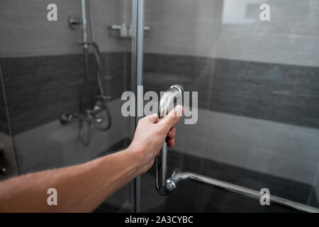 Männliche Hand öffnet die Tür Dusche in einem modernen Badezimmer. Stockfoto