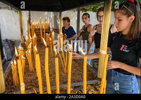 Junge Frauen Beleuchtung Kerzen in einem orthodoxen Schrein während eines Festivals in der Stadt Messini, Peloponnes, Griechenland. Stockfoto