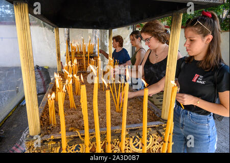 Junge Frauen Beleuchtung Kerzen in einem orthodoxen Schrein während eines Festivals in der Stadt Messini, Peloponnes, Griechenland. Stockfoto