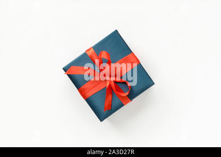 Blauen Geschenkbox mit roter Schleife auf weißem Hintergrund. Ansicht von oben. Copyspace Stockfoto