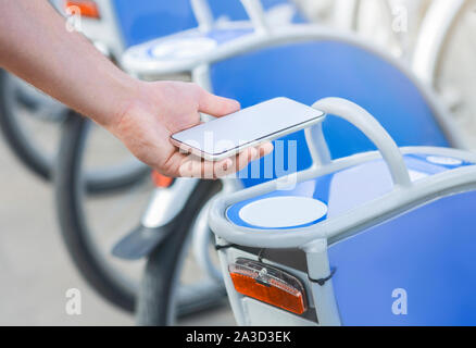 Mann Entriegelung Fahrräder durch Scannen Code auf Rack outdoor Stockfoto