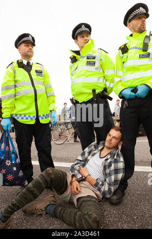 Polizei in Gelb hohe gegenüber Mäntel Verhaftung ein Klima demonstrant als Aussterben Aufstand begann zwei Wochen Protest gegen Untätigkeit über die Klimakrise in Westminster mit zahlreichen Straßensperren, einschließlich Westminster und Lambeth Brücken. Proteste außerhalb des Parlaments, die Westminster Abbey, Downing Street und DEFRA führte im gesamten Bereich für den Verkehr gesperrt werden. Stockfoto