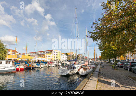 Kopenhagen, Dänemark: Bäume mit herbstlichen Farben line Overgaden Backofen Vandet in Christianshavn. Yachten sind gegen den gepflasterten Hafenmauer festgemacht. Stockfoto