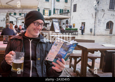 Gut aussehender Mann mittleren Alters lesen Montenegro Reiseführer Stockfoto