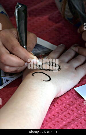 Künstler, die Anwendung von Henna-Tattoo auf Frauen Hände. Mehndi ist die traditionelle indische dekorative Kunst. Close-up Stockfoto