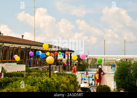 Mitte August Party in einer Badeanstalt mit bunten Luftballons und Touristen, einen Swimmingpool am Strand von Viareggio, Toskana, Italien Stockfoto