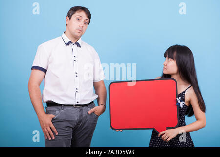 Asiatische freundin Holding leere Blase Gedanken und ihr verwirrt kaukasischen Freund. Interracial Paare. Stockfoto