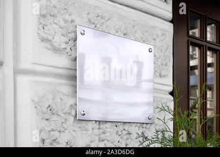 Schilder aus leerem silbernen Glas auf strukturiertem Wandmockup Stockfoto