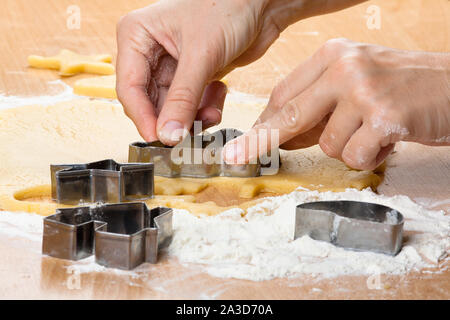 Hände von Frau schneiden Cookies aus dem Teig, Nahaufnahme Stockfoto