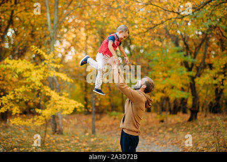 Vater spielt mit seinem Sohn und wirft ihn beim Gehen in den Wald. Stockfoto