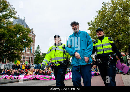 Ein älterer Mann und XR Aktivist festgehalten wird, die von der Polizei während des Protestes. Für 2 Wochen, Aussterben Rebellion und verwandter Bewegungen werden in den großen Städten auf der ganzen Welt sammeln und weiterhin rebellieren gegen die Regierungen der Welt für ihre kriminellen Untätigkeit auf das Klima und die ökologische Krise zu. XR Klima Aktivisten in Amsterdam werden eine große Blockade über mehrere Tage auf der Museumbrug zu organisieren, vor dem Rijksmuseum. Von früh am Morgen, Hunderte von XR Aktivisten auf der Brücke, wo es eine sichtbare Polizeipräsenz. Die Umweltorganisation extinc Stockfoto