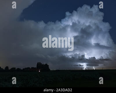 Gewitter über die niederländische Landschaft ist durch Blitz beleuchtet. Mehrere Blitze schlagen auf die Erde von diesem Sturm. Stockfoto